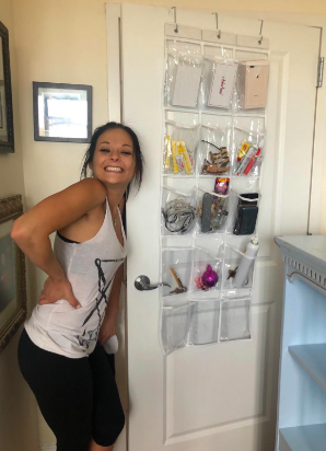 A reviewer smiling beside the pocket organizer, now filled with bathroom essentials stored in the clear pockets.