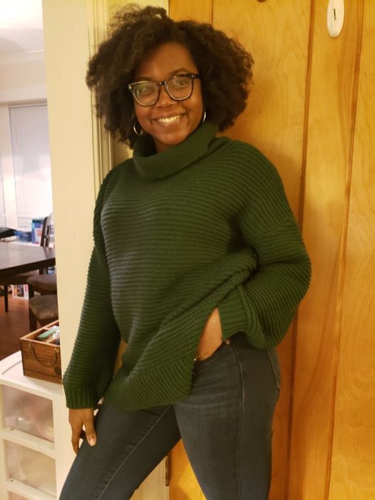 A customer review photo showing them wearing the sweater in dark green