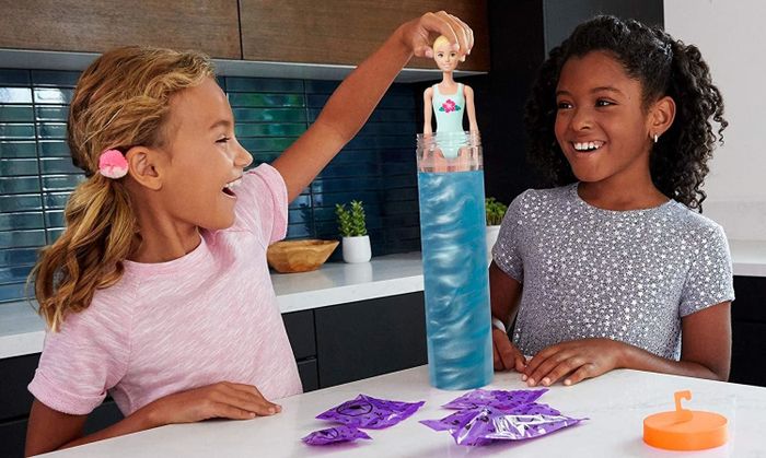 Two kids playing with the Color Reveal Barbie, dipping her into the color-changing water.