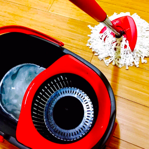 A reviewer demonstrating the use of a small mop to clean the floor, with soapy water in a bucket
