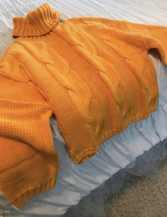 A customer review photo of the sweater neatly laid out on their bed