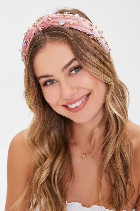 A model showcases a pink velvet headband, encrusted with delicate jewels.
