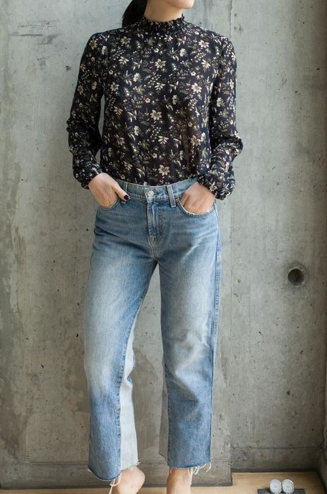 A reviewer showcasing the floral top in dark blue, tucked neatly into denim jeans