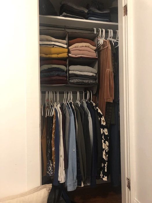 A reviewer's closet featuring a four-cube organizer filled with sweaters, with tops hanging from the rod at the bottom of the organizer