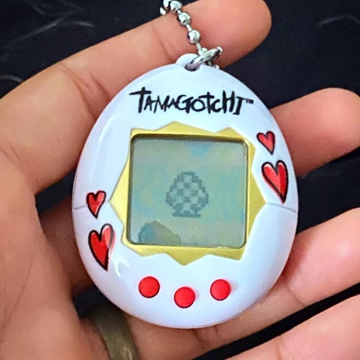 A reviewer’s white Tamagotchi case featuring red hearts and red buttons.