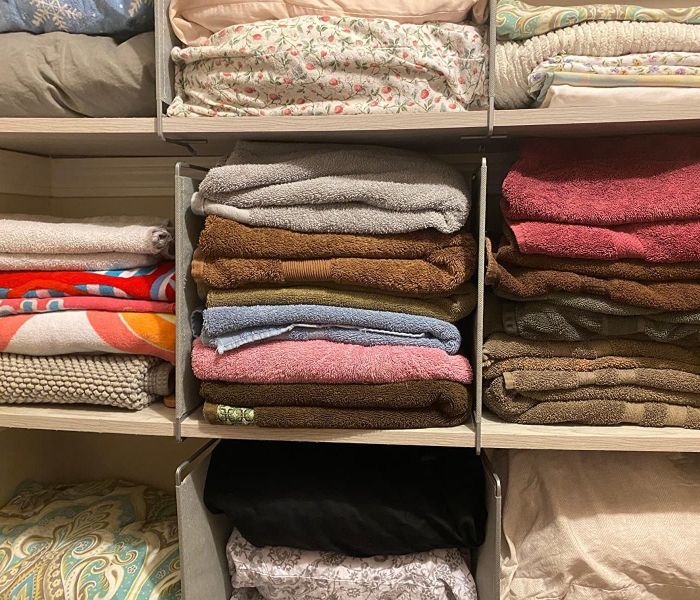 A reviewer’s photo showing a closet neatly filled with linens, organized using the dividers.