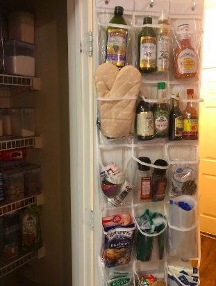 A reviewer’s pantry with an over-the-door organizer, featuring five levels of clear pockets filled with bottles, spices, and various kitchen tools.