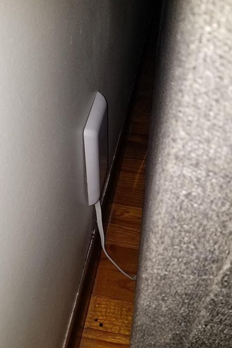A reviewer’s photo featuring the slim socket cover, with a piece of furniture pushed neatly against the wall.
