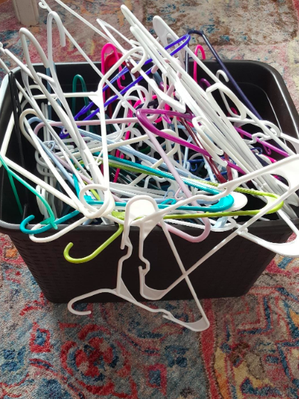 A container overflowing with hangers in a disorganized mess.