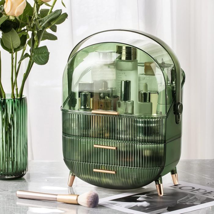 A green beauty organizer with textured material and gold detailing, filled with skincare products