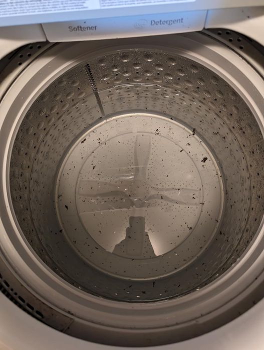Top-down view of a reviewer’s washing machine drum, with visible dirt and debris inside