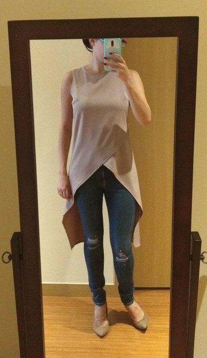 A reviewer styling the light pink long blouse over jeans
