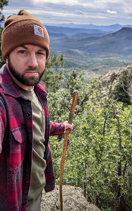 A male reviewer is pictured wearing the brown beanie while hiking.