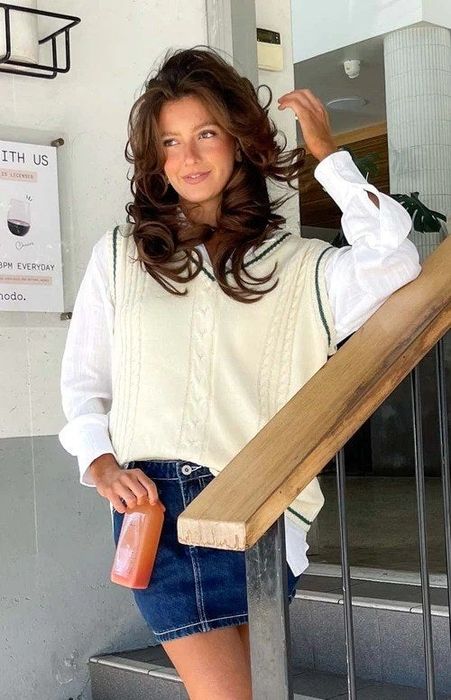 A different model wearing a white long-sleeve shirt under the white cable-knit sweater vest