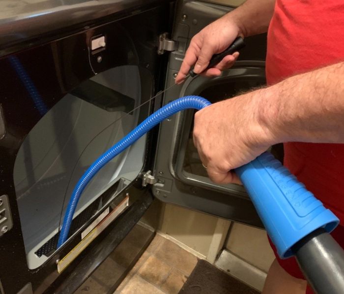 A reviewer demonstrating the use of the dryer vent cleaner.