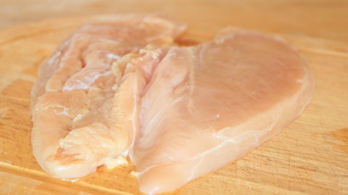 A butterflied chicken breast placed on a cutting board.