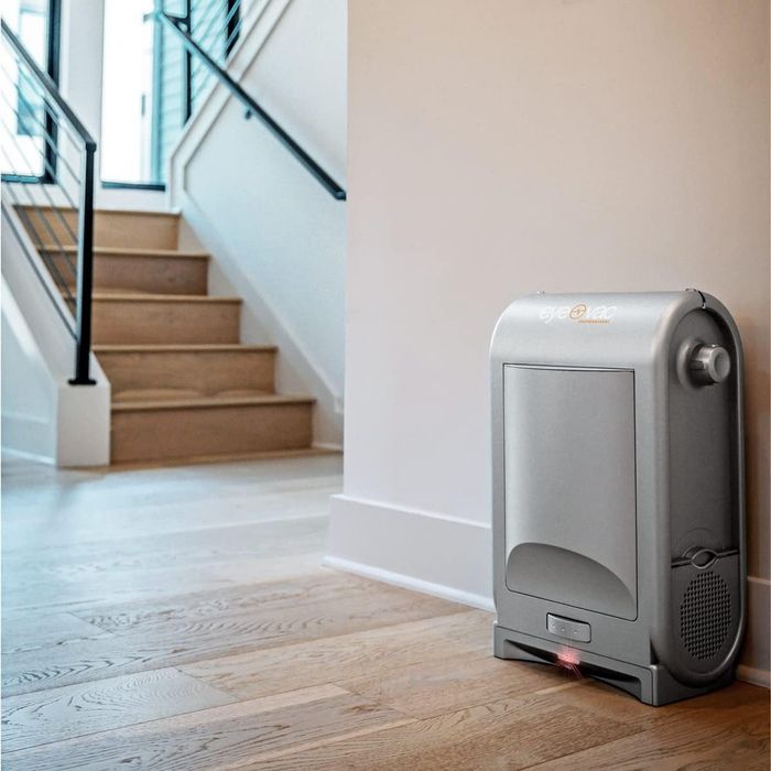 A sleek, modern home air purifier positioned on a wooden floor next to a staircase, blending effortlessly into contemporary home decor.