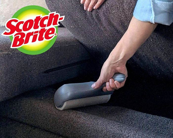 A person using the handheld roller beneath their couch cushion.