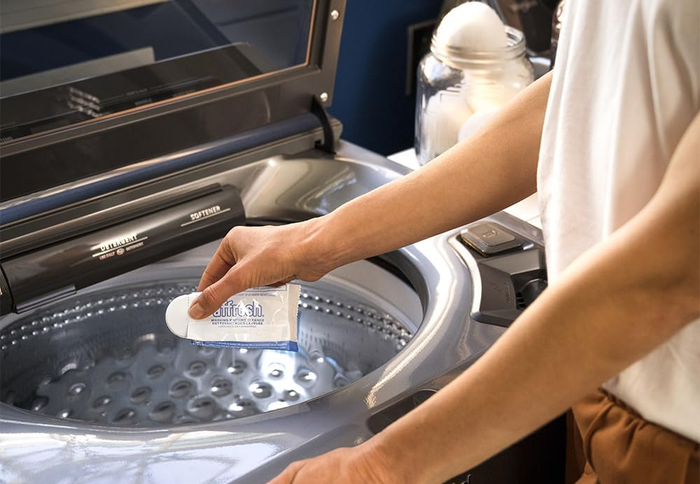Person adding Affresh washing machine cleaner to a washing machine