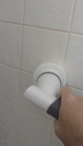a gif of the reviewer using the electric scrubber to clean tile surfaces
