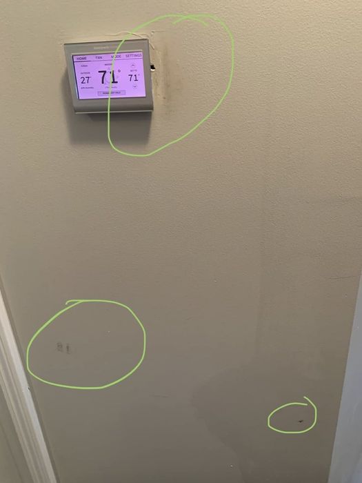 A thermostat shows a temperature reading of 71°F. Green circles highlight several marks found on the wall below and beside the thermostat.