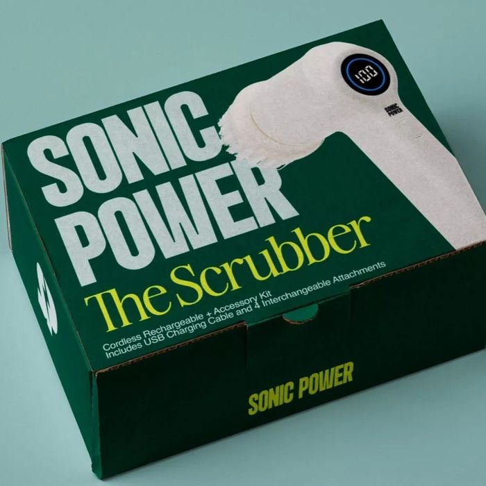 The packaging for the Sonic Power Scrubber displays a rechargeable device with multiple interchangeable brush heads, along with a USB charging cable.