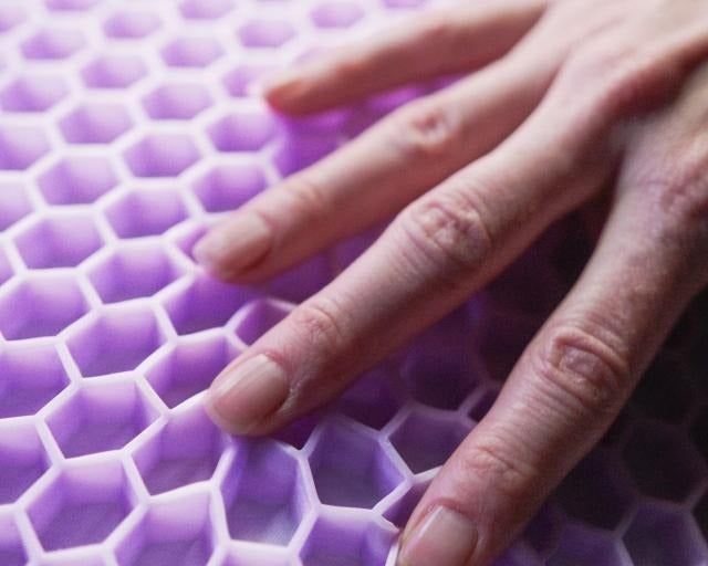 A model's hand resting on the unique purple flex grid pillow design