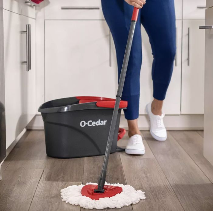 An O-Cedar mop and bucket in use in a kitchen setting.