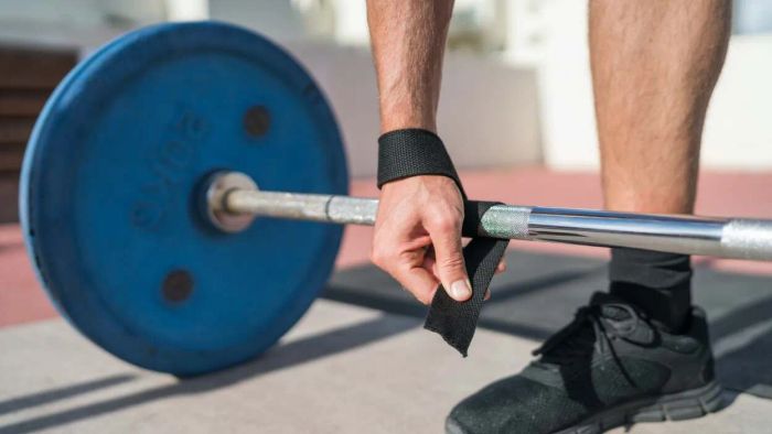 securing a strap around a barbell during deadlifts