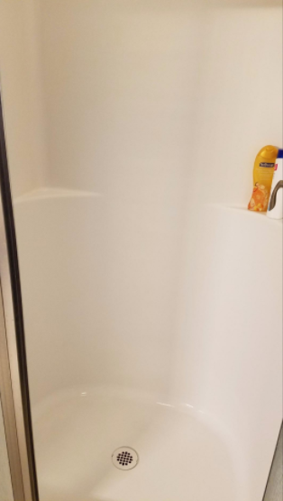 A follow-up photo from the same reviewer showing the shower with significantly less rust after using the spray gel.