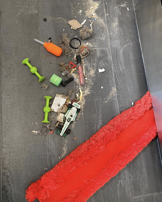 Reviewers share an image of a red duster next to a heap of forgotten items discovered beneath the oven.