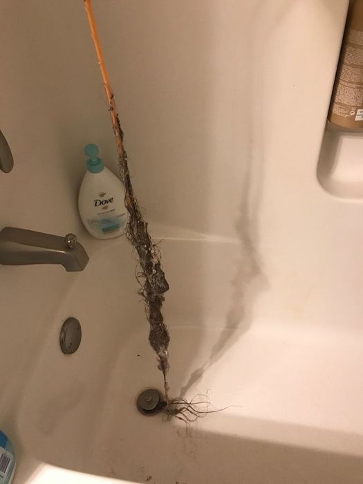 Reviewer holding the drain snake, which has pulled out a large clump of hair from the drain