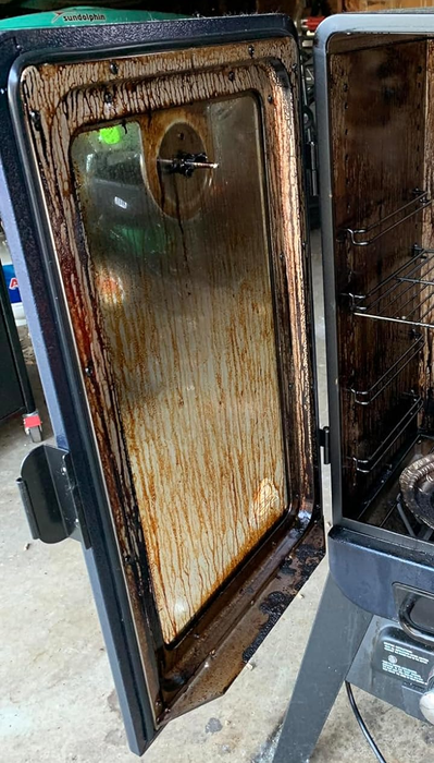 A door of a smoker covered in grease and grime