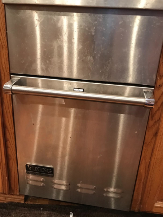 A stainless steel dishwasher covered in streaks, buildup, and marks
