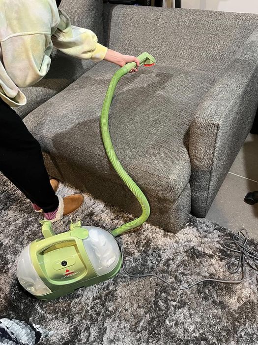 Reviewer using the Bissell Little Green on a couch