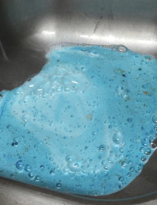 A sink filled with blue liquid, showing the use of a cleaning solution.