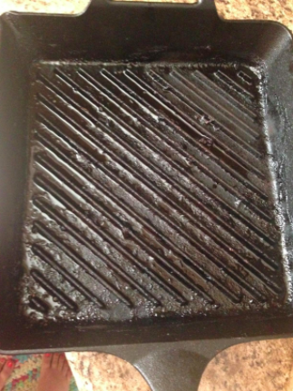 A before photo of a reviewer's cast-iron pan, heavily coated with burnt food residue.