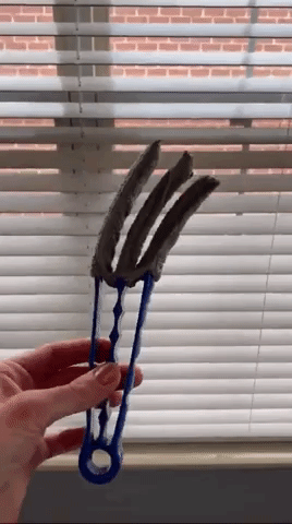 A gif of a person holding the duster brush and twisting it. The brush resembles tongs but features three prongs instead of two.