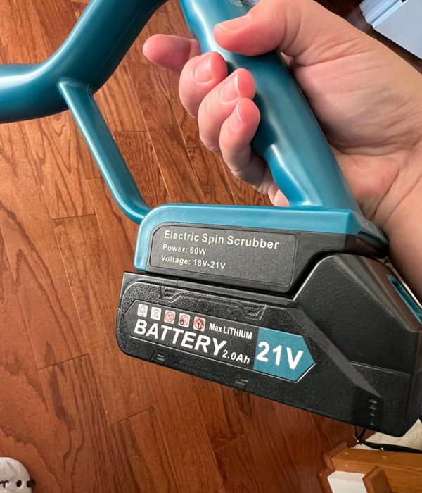 the reviewer holding an electric spin scrubber featuring a 21V battery