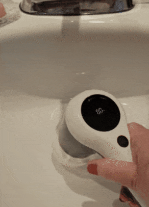 A gif showing the reviewer using an electric spin scrubber to clean a sink.