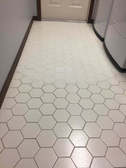 A reviewer's photo of a tile floor, with one half showing stained grout and the other half appearing freshly cleaned.