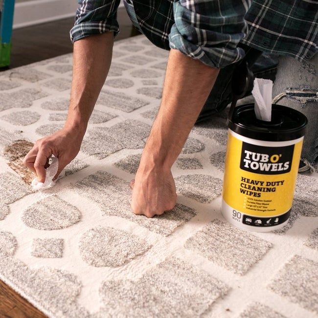 A model demonstrating the use of cleaning wipes on a carpet with visible stains