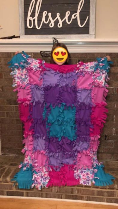 A reviewer's photo showing their child proudly holding up the quilt they made