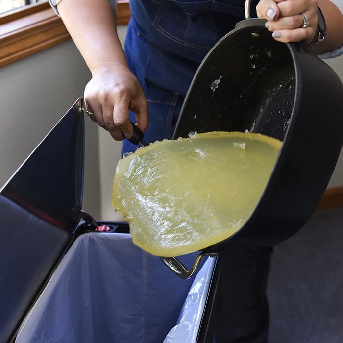 The model scoops up a large chunk of hardened grease and throws it away in the trash.