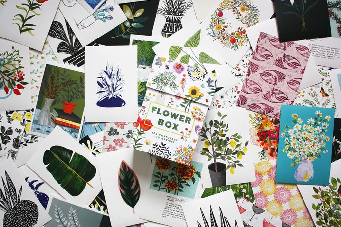 Box of postcards displayed on a table, filled with various postcard designs