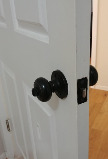 A door slightly ajar, featuring a sleek black round doorknob.