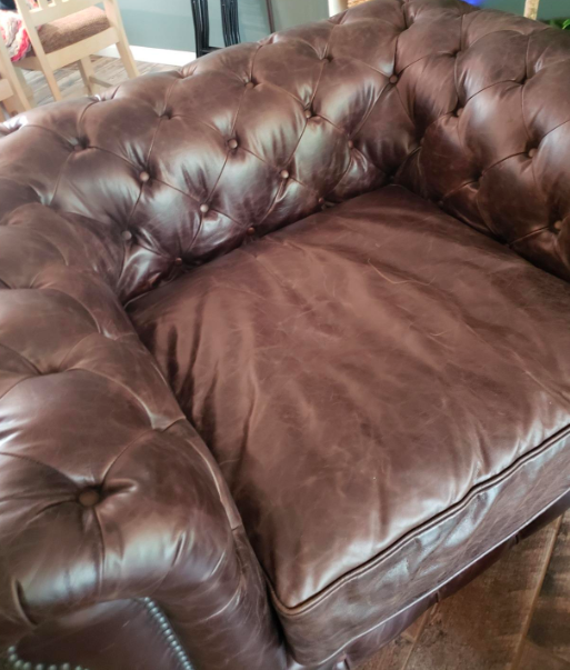 A reviewer's before photo showing a dull, brown leather armchair in need of some attention.