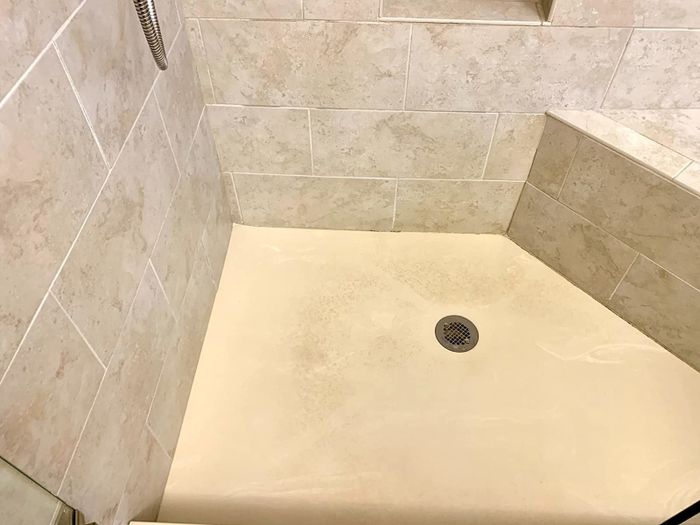 A photo showing a shower floor covered in dirt and stains.