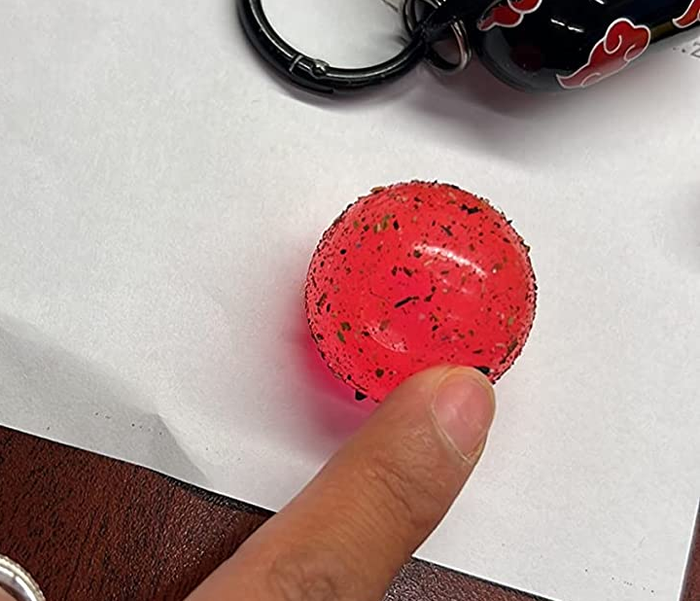 The reviewer points to the dirt that the Clean Ball has gathered from their bag.