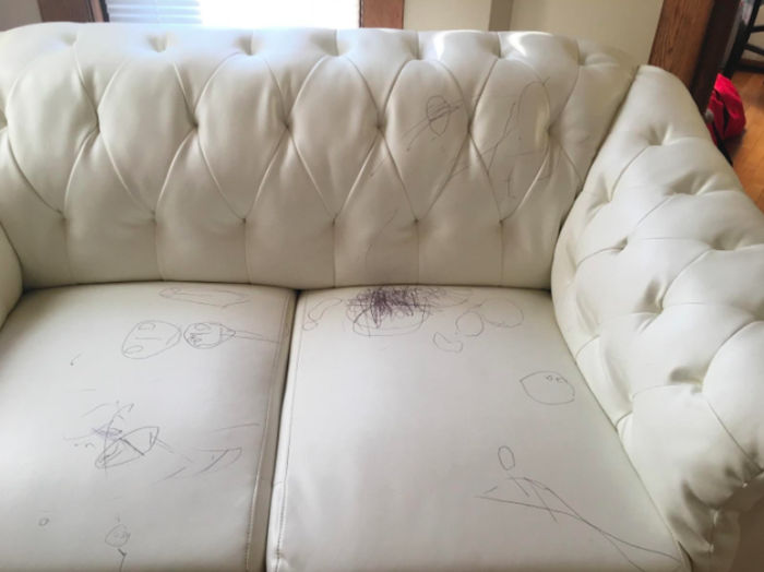 A white leather sofa marked with numerous pen scribbles all over its surface